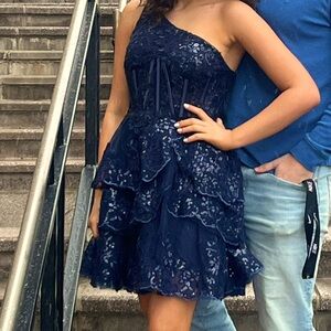 Size 0. Navy mini dress.  Can fit a size or 2 up as the back is tie up.